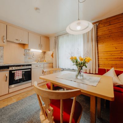 Helle Wohnküche der Ferienwohnung Hochjoch, moderne Küchenzeile und gemütliche Sitzecke vor Holzwand
