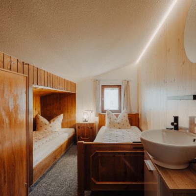 Kinderzimmer der Ferienwohnung Hochjoch, mit zwei Einzelbetten, kleinem Fenster und Waschbecken