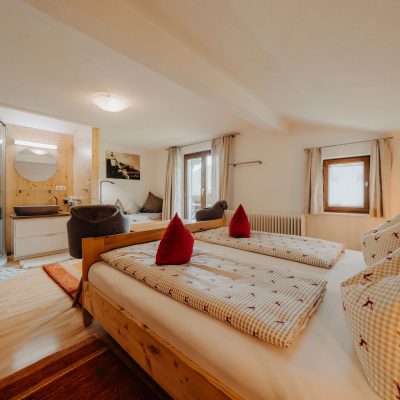 Helles Schlafzimmer der Ferienwohnung Hochjoch, Ausblick auf Doppelbett, Waschbecken und Balkontür