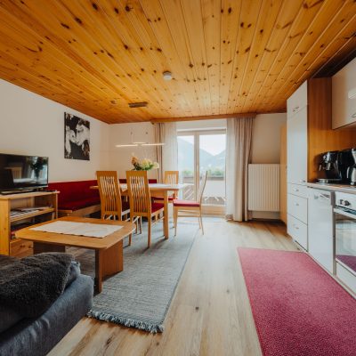 Helle Wohnküche der Ferienwohnung Mittagspitze im Haus Wilma, im gemütlichen, natürlichen Stil mit Holzdecke, roter Sitzecke und moderner Küchenzeile.